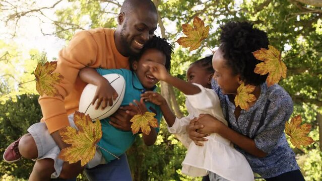 Animation of fall leaves over happy african american family in autumn park