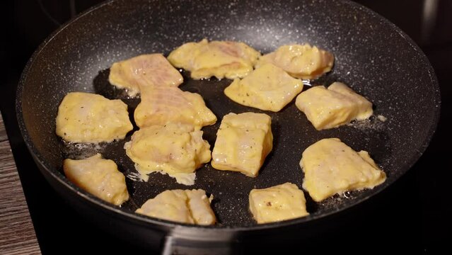 pieces of white fish in dough are fried in a pan. home cooking