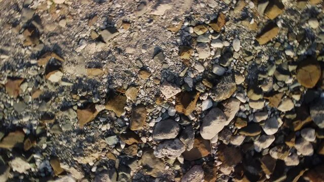 Rocky stones are lying on the ground and filmed from above by drone at summer day. Closeup footage of rubbles of different size and shape on earth. Natural fossils and gravel in the environment theme.
