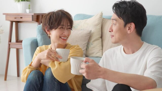 リビングでコップを持ち仲良く話す若い日本人カップル