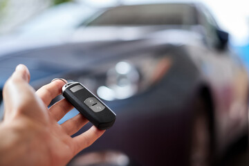 The car owner holds in his hand a remote control device for keyless entry. Close-up, selective focus