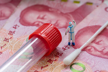 miniature doctor stand on China paper currency. Concept of concept of making money from Covid-19...