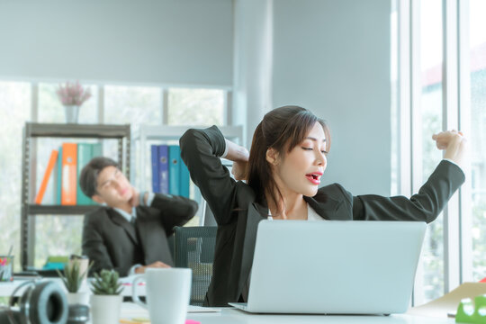 Female Asian Businesswoman Worker Is Stretching And Yawn In Office Workplace, After A Long Time Of Sleepy Work.