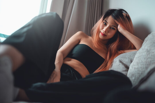 Sporty Asian woman is posing cool on sofa with seductive active black clothing for Street Girl fashion style.