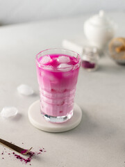 Pink matcha tea with ice and milk in crystal glass on white kitchen.Close up of detox drink.