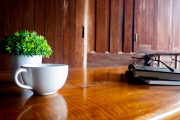 Cropped shot view of wood office desk table with the cup of coffee,office equipments, and other office supplies on the modern space, flat lay.
