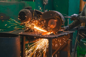 A factory worker cuts metal. Production