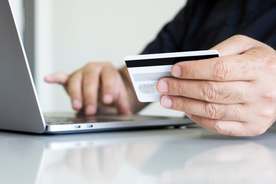 Male hands holding credit card and using laptop. Online shopping concept photo with copy space area.