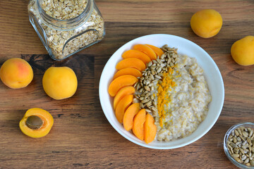 morning cereal with apricot, seeds and turmeric on wooden background