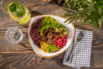 Salad bowl with fresh tofu, avocado, lettuce, grenade apple and mango, top view