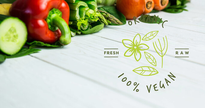Image of 100 percent vegan text in green over fresh organic vegetables on wooden boards