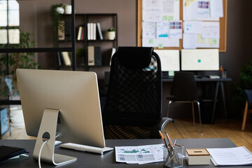 Image of workplace of manager with computer monitor and documents on desk at modern office