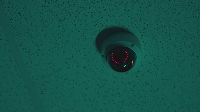 Security circle camera switching on or off and recording what's happening inside building . Night vision panoramic 360 degree security camera hangs on roof inside parking or office . Security concept