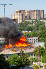 Fototapeta premium Old and new. An old abandoned building is burning against the background of new buildings