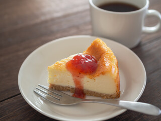 苺のソースをかけたベイクドチーズケーキとコーヒー