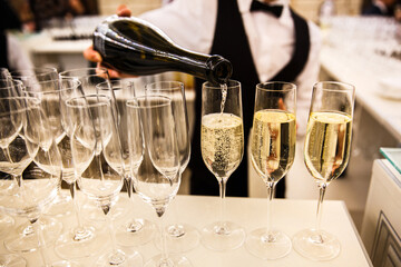 The waiter pours champagne into a glasses
