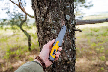 Plastic knife with yellow handle, hiking knife, bracelet on hand, hold the knife in your hands.