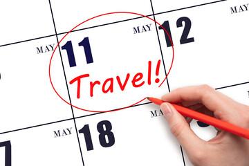 Hand drawing a red circle and writing the text TRAVEL on the calendar date 11 May. Travel planning.