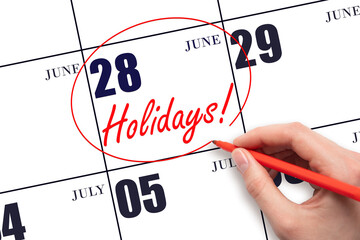 Hand drawing a red circle and writing the text Holidays on the calendar date 28 June. Important...