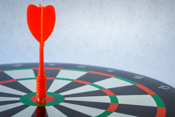 Red dart arrow hitting in the target center of dartboard on white background, Target marketing and...