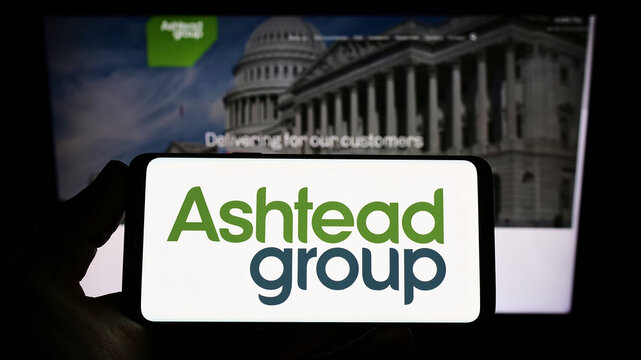 Stuttgart, Germany - 05-29-2022: Person holding smartphone with logo of equipment rental company Ashtead Group plc on screen in front of website. Focus on phone display.