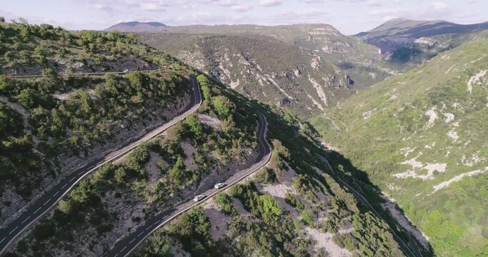 Aerial drone view of cars passing through curve roads on serpentines in France