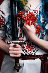 Ukrainian girl with a sword in vyshyvanka with viburnum in her hands on a red background. idea war in Ukraine attack Russia