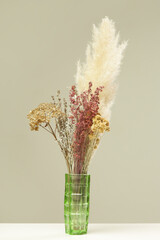 Green vase with bunch of various dried flowers and plants