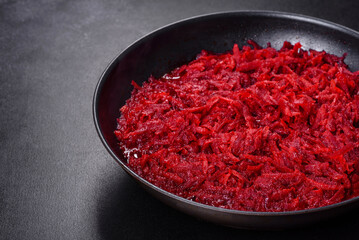 Chopped beetroot in a pan as well as spices and herbs on a wooden cutting board