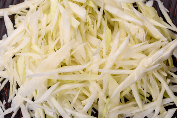 Part of a cabbage head and chopped cabbage salad on wooden cutting board