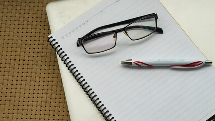 Office desk table and book note with glasses pen top view
