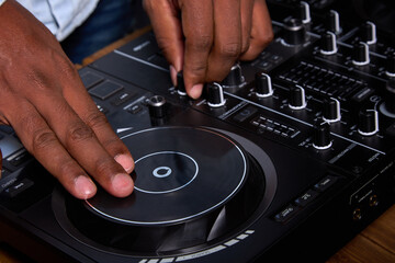 A DJ console or mixer is used to combine different audio sources into one output. Hands of a dark...