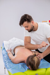 At medical clinic the massage therapist man using a wooden stick to massaging professional the back...