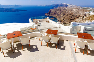 Empty restaurant tables on a sunny terrace in Santorini.