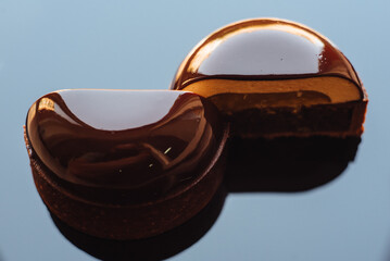 A modern tropical mini-mousse covered with a mirror glaze. Mini chocolate mousse cake on a blue background, top view. Modern European dessert