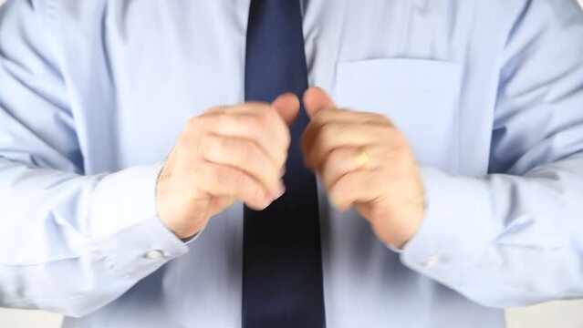 A man in a blue shirt and tie cracks the knuckles of his hands and fingers, demonstrating knuckle-cracking or knuckle joints. Medical Concept