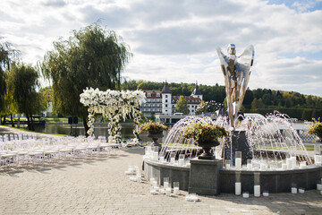 Outdoor wedding ceremony by the lake near the fountain