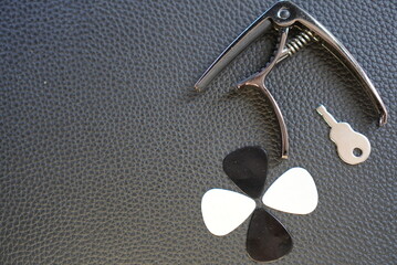 Objects to play guitar on leather surface, guitar plectrum, guitar capo, jack cable