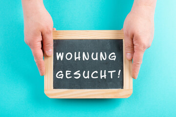 Holding a chalkboard in the hands, looking for an apartment is standing in german language on the...