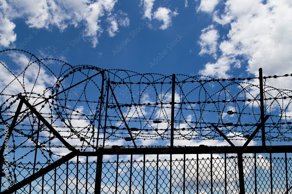 Wall mural Сontour of barbed wire on background beautiful clouds and sky