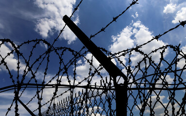 Сontour of barbed wire on background beautiful clouds and sky