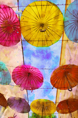 Color umbrellas hang against the background of the blue sky, watercolor illustration