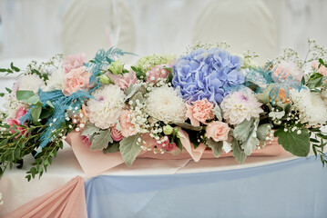 Obraz na płótnie Canvas Lush floral arrangement on wedding table in restaurant, copy space. Luxury wedding decorations. Banquet table for newlyweds with white, pink and blue flowers.