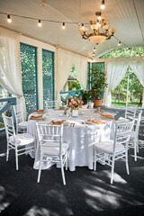 Table setting with sparkling wineglasses, plate with brown napkin and cutlery on table outdoors, copy space. Place set at wedding reception. Table served for wedding banquet in restaurant