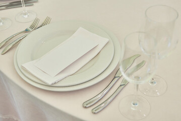 Table setting with sparkling wineglasses, plate with white napkin and cutlery on table, copy space. Place set at wedding reception. Table served for wedding banquet in restaurant
