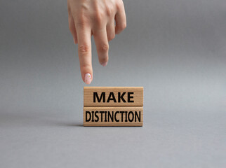 Make distinction symbol. Concept words make distinction on wooden blocks. Beautiful grey background. Businessman hand. Business and make distinction concept. Copy space.