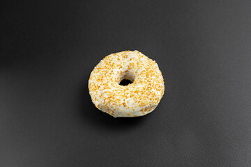 Biscuit donut with white icing on a black background.
