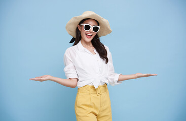 Happy beautiful Asian woman dressed in summer clothes smiling with open hand gesture of welcome...