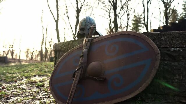 Schwert lehnt an einem Schild aus Holz mit einem Wikinger Ritter Helm
