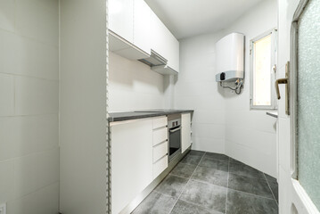 Kitchen with newly installed cabinets and drawers in a simple apartment with gray tile floors,...